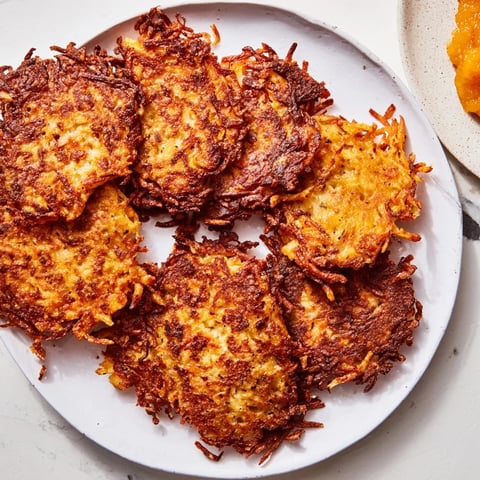 Crispy potato pancakes topped with sweet applesauce, perfect for brunch delights.  